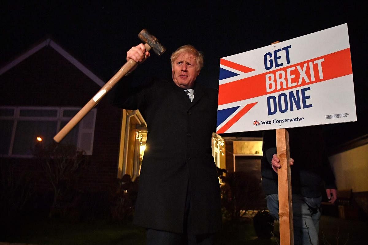 Britain's Prime Minister and Conservative party leader Boris Johnson poses after hammering a "Get Brexit Done" sign into the garden of a supporter, with a sledgehammer as he campaigns with his team in Benfleet, east of London. AFP