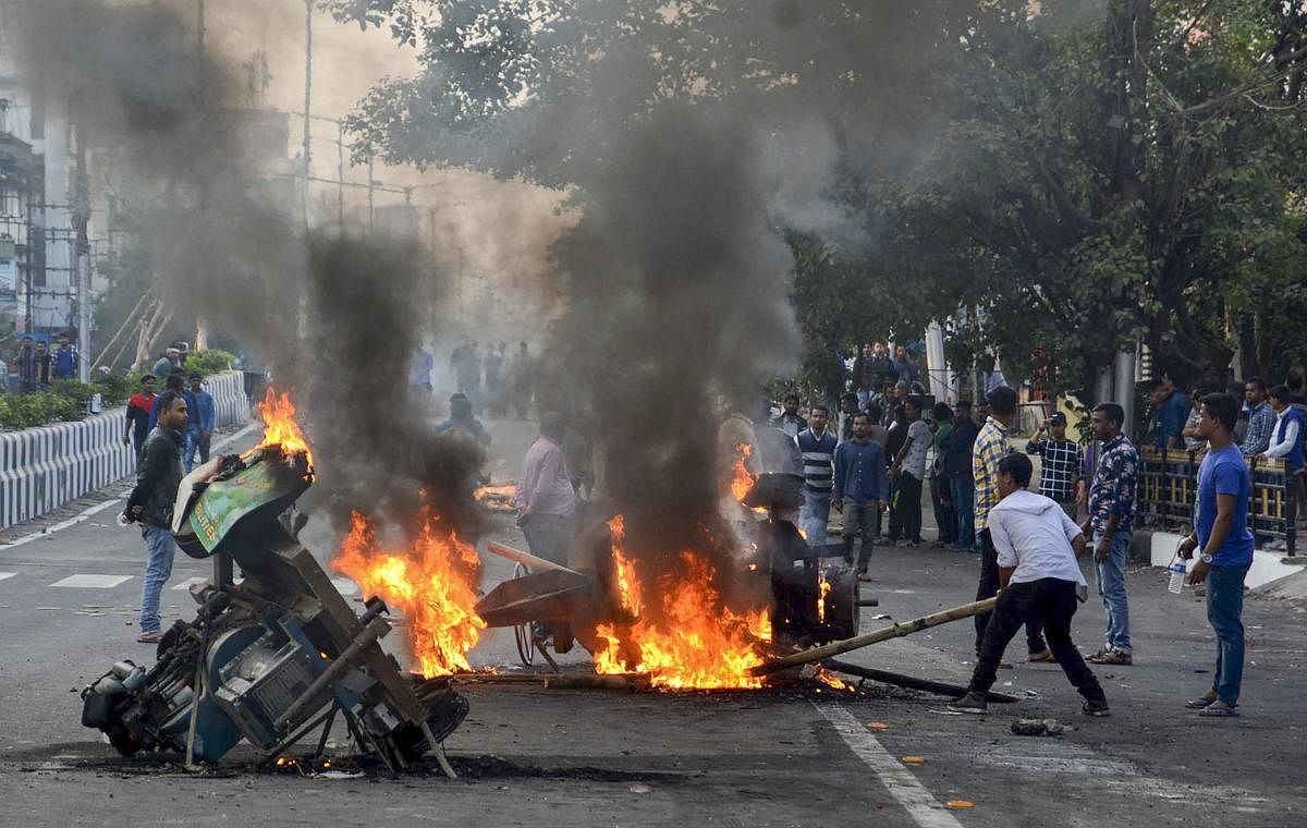 Protesters burn machinery to block a road during an agitation against the Citizenship Amendment Bill in Guwahati on Thursday. PTI