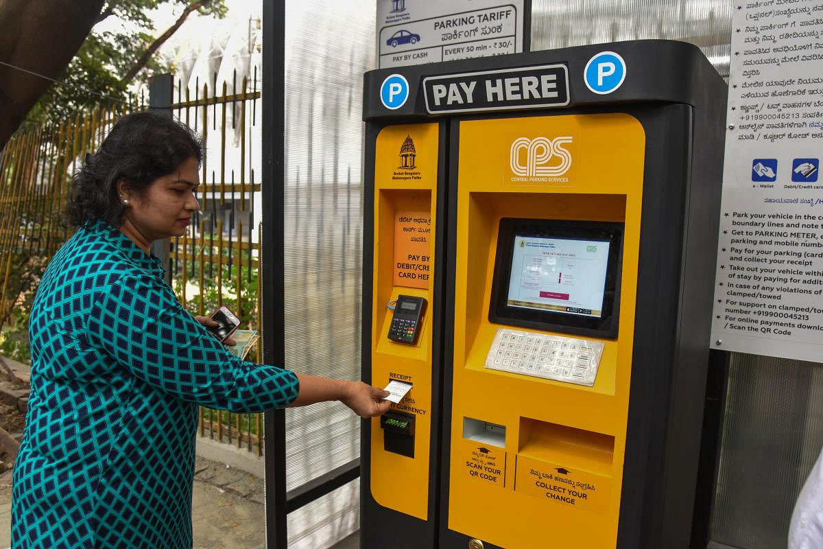  People paying in pay machine at Smart Car Parking trail work is going on by BBMP maintain by Central Parking Services at Kasturba Road in Bengaluru on Saturday. (Photo by S K Dinesh)