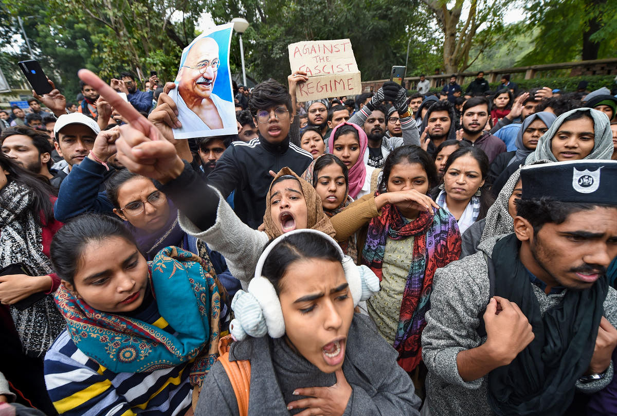 Activists of All India Students Association (AISA) raise slogans during a protest against the Sunday's police action at Jamia Milia Islamia, on the campus of the Delhi University. PTI