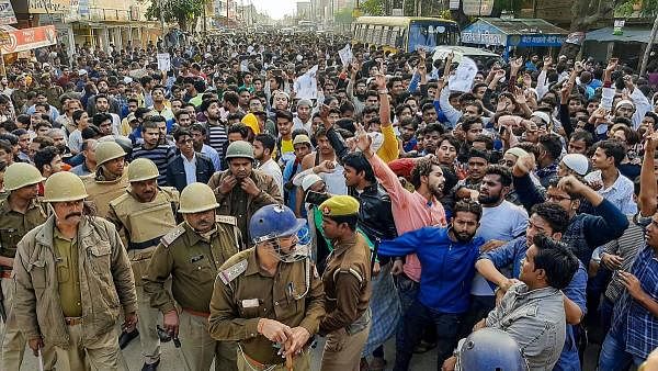 Police keep a watch as Muslim people shout slogans during a protest against Citizenship Amendment Act, at Mirza Hadipur Chowk in Mau, Monday, Dec. 16, 2019. (PTI Photo)