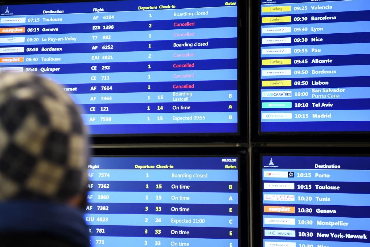 In this file photo taken on December 5, 2019 a man looks at the information board reading the different planes cancelled during a strike over French government's plan to overhaul the country's retirement system, at the Paris Orly airport in Orly, as part