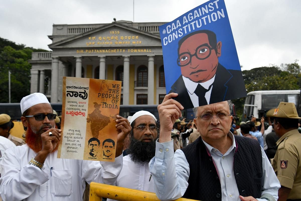 Historian Ramchandra Guha (R) holds a placard against India's new citizenship law during a protest held in spite of a curfew in Bangalore on December 19, 2019.