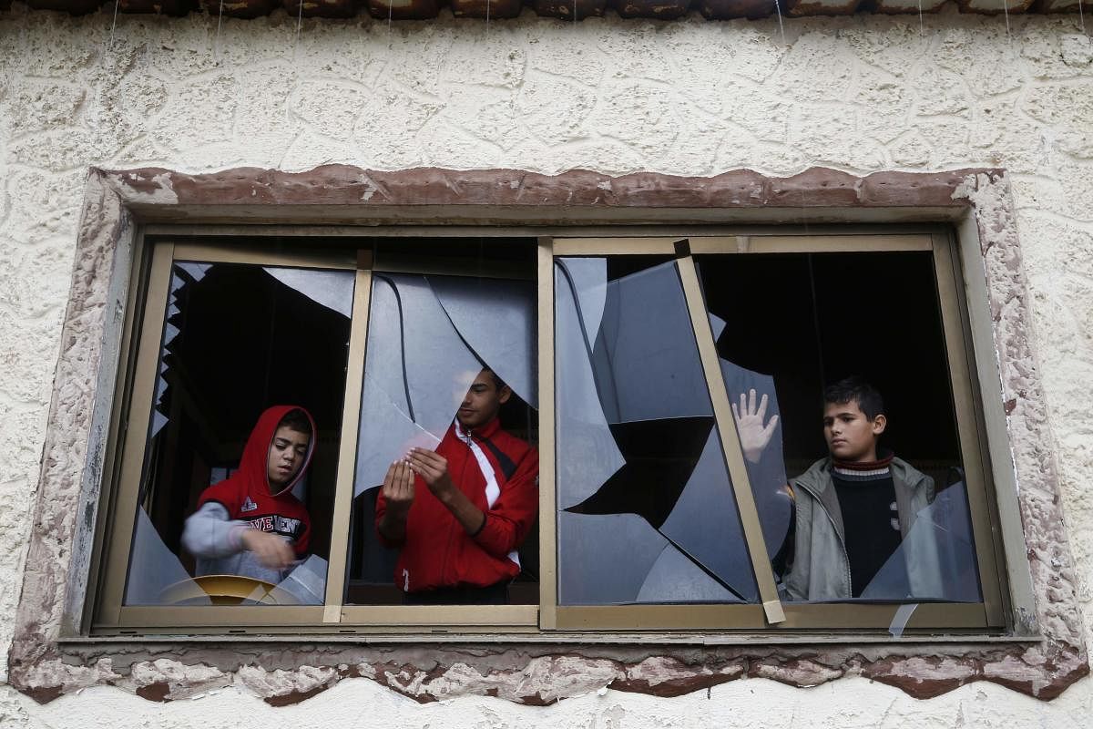Palestinian boys pull shards of glass from a broken window at their home near the site of attacks by Israeli aircraft in the Hamas-controlled Gaza Strip. (AFP Photo)