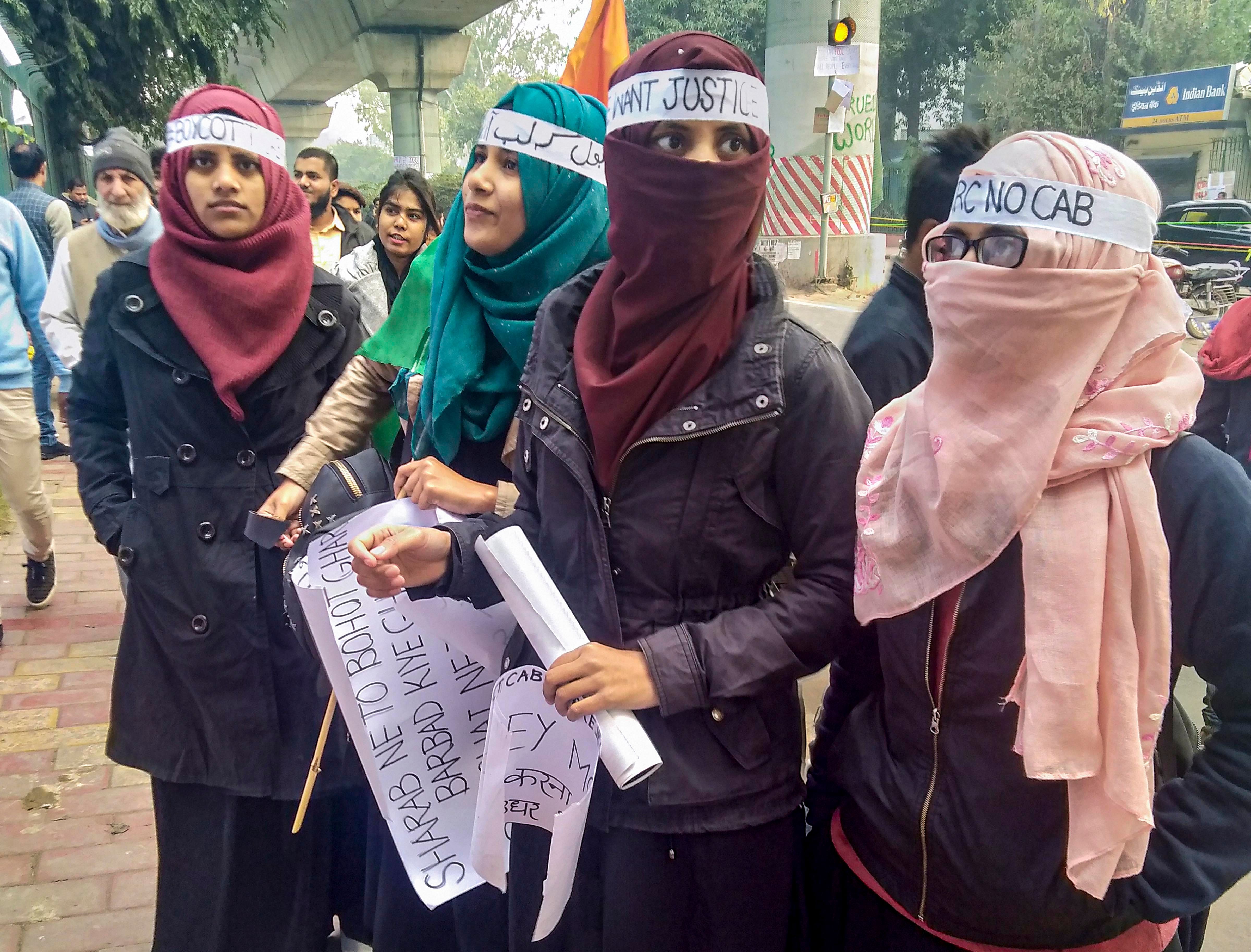 Protestors hold placards during a demonstration against the Citizenship Amendment Act (CAA) outside Jamia Milia Islamia University. (PTI Photo)