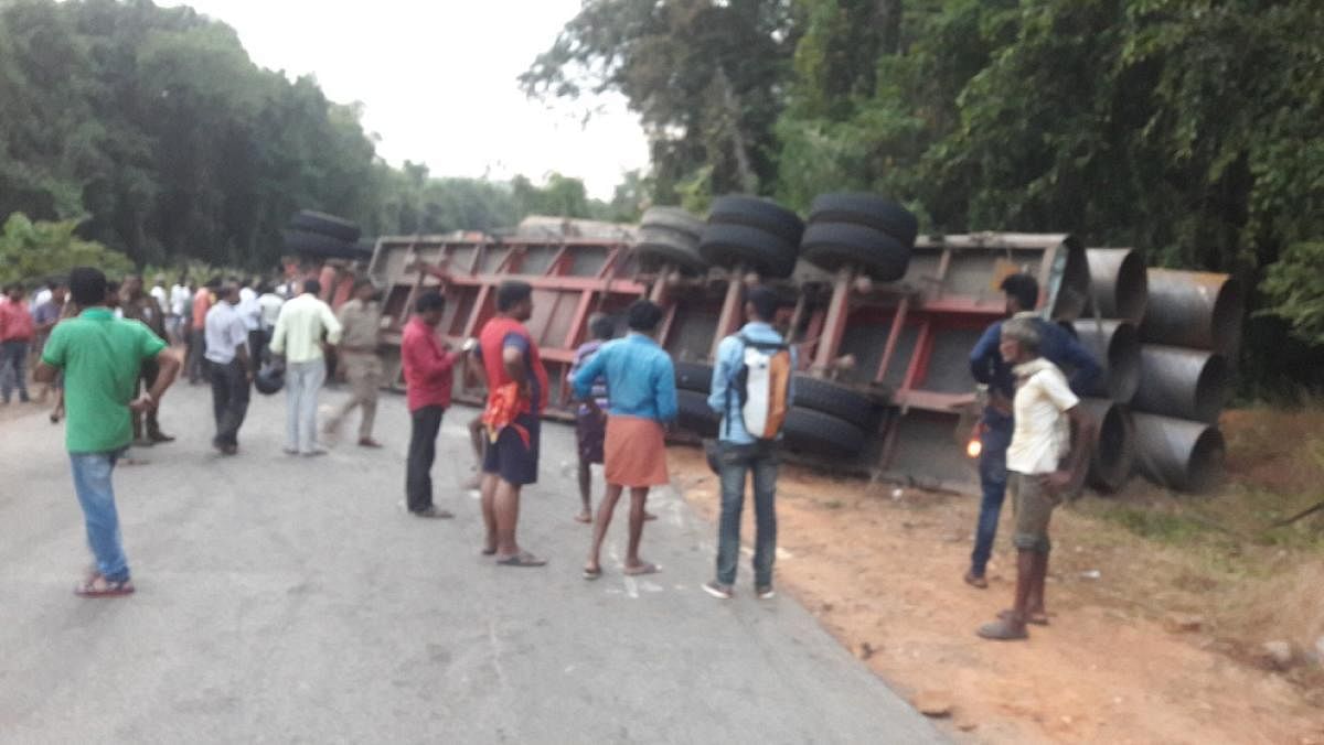 A trailer carrying huge pipes toppled and fell on the car crushing it instantaneously at Paravara Kotya near Udane on NH 75 in Shiradi Ghat on Friday evening.