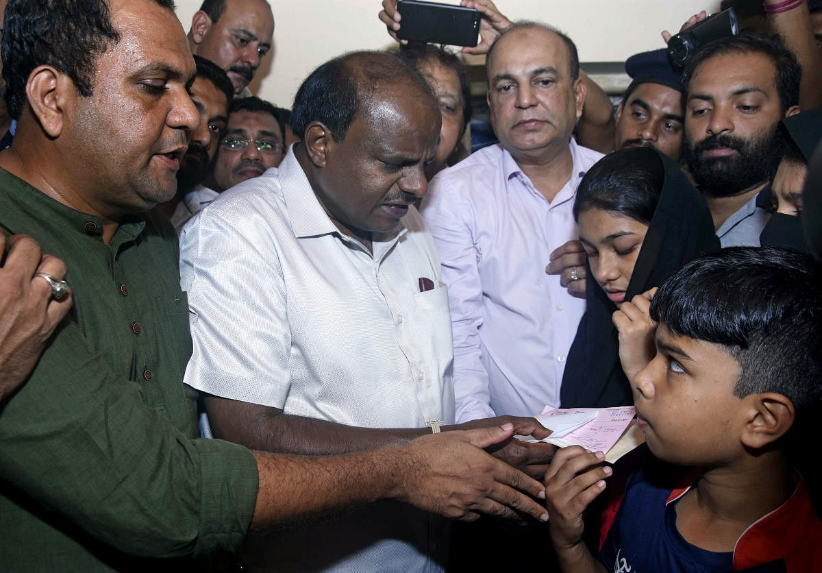 Former chief minister H D Kumaraswamy hands over a cheque of Rs 5 lakh to the children of Ahmmed Jaleel, who was killed in police firing, at his residence at Kandak, in Mangaluru on Sunday. DH Photo