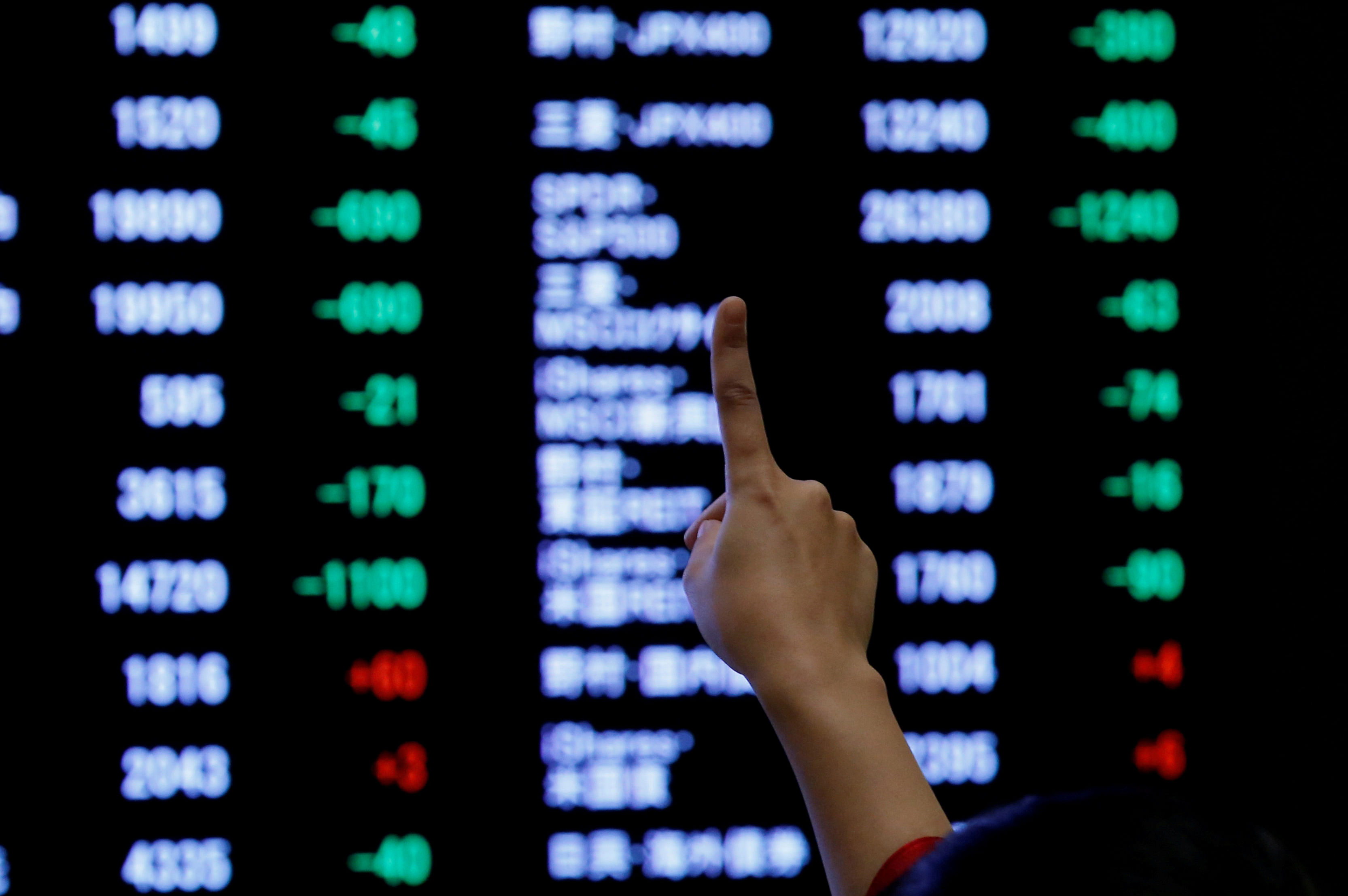  A woman points to an electronic board showing stock prices as she poses in front of the board after the New Year opening ceremony at the Tokyo Stock Exchange (TSE), held to wish for the success of Japan's stock market, in Tokyo, Japan, January 4, 2019. (Reuters Photo)