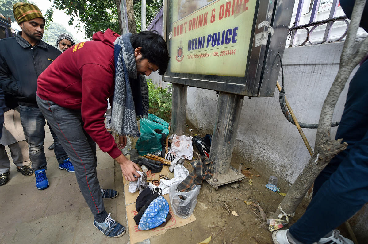 A member of an NGO watches articles of violent protesters and broken police batton sticks after a rally against the Citizenship Amendment Act (CAA). PTI