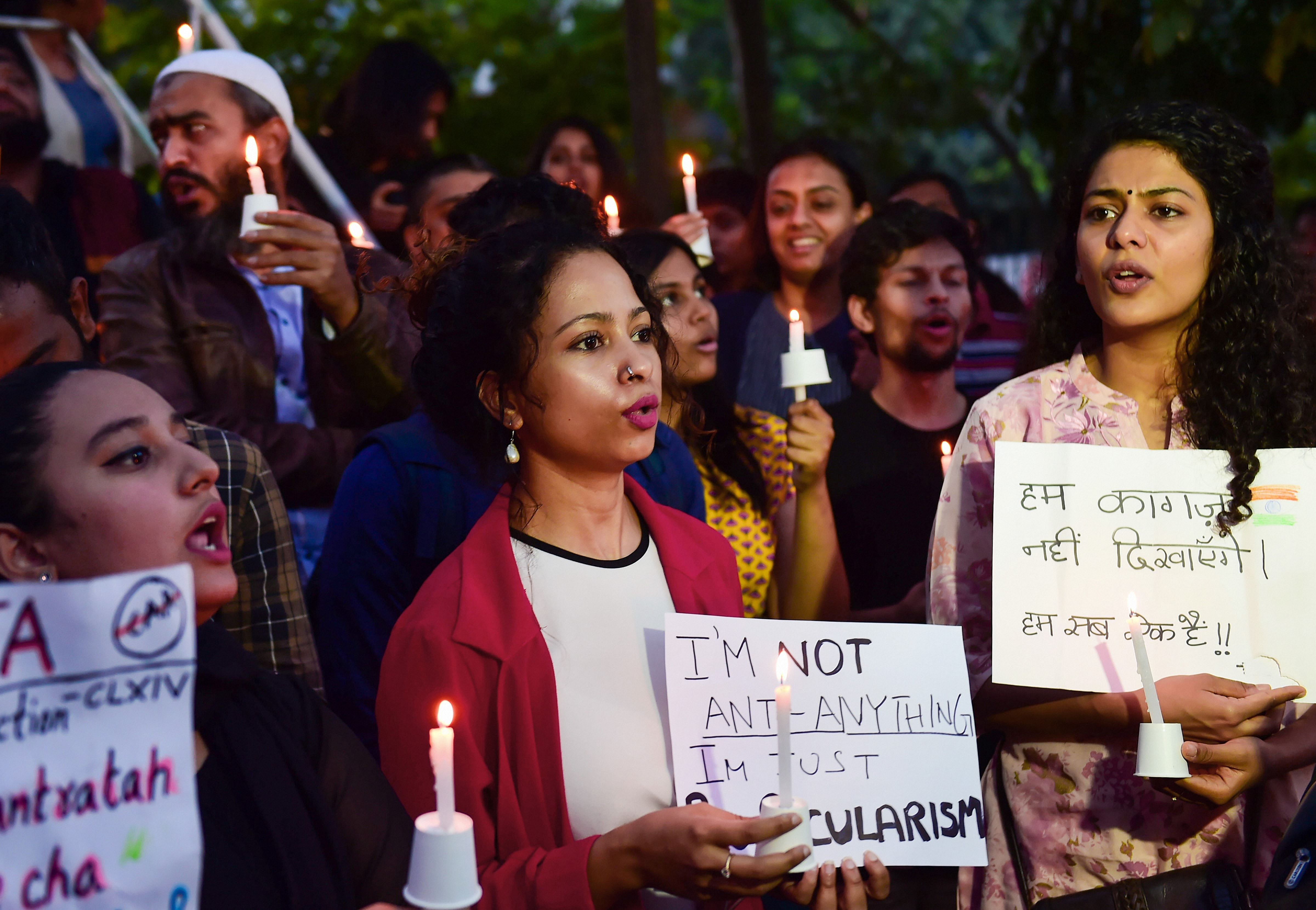 Protestors hold placards as they raise slogans during an anti-Citizenship Act candle light protest. (PTI Photo)