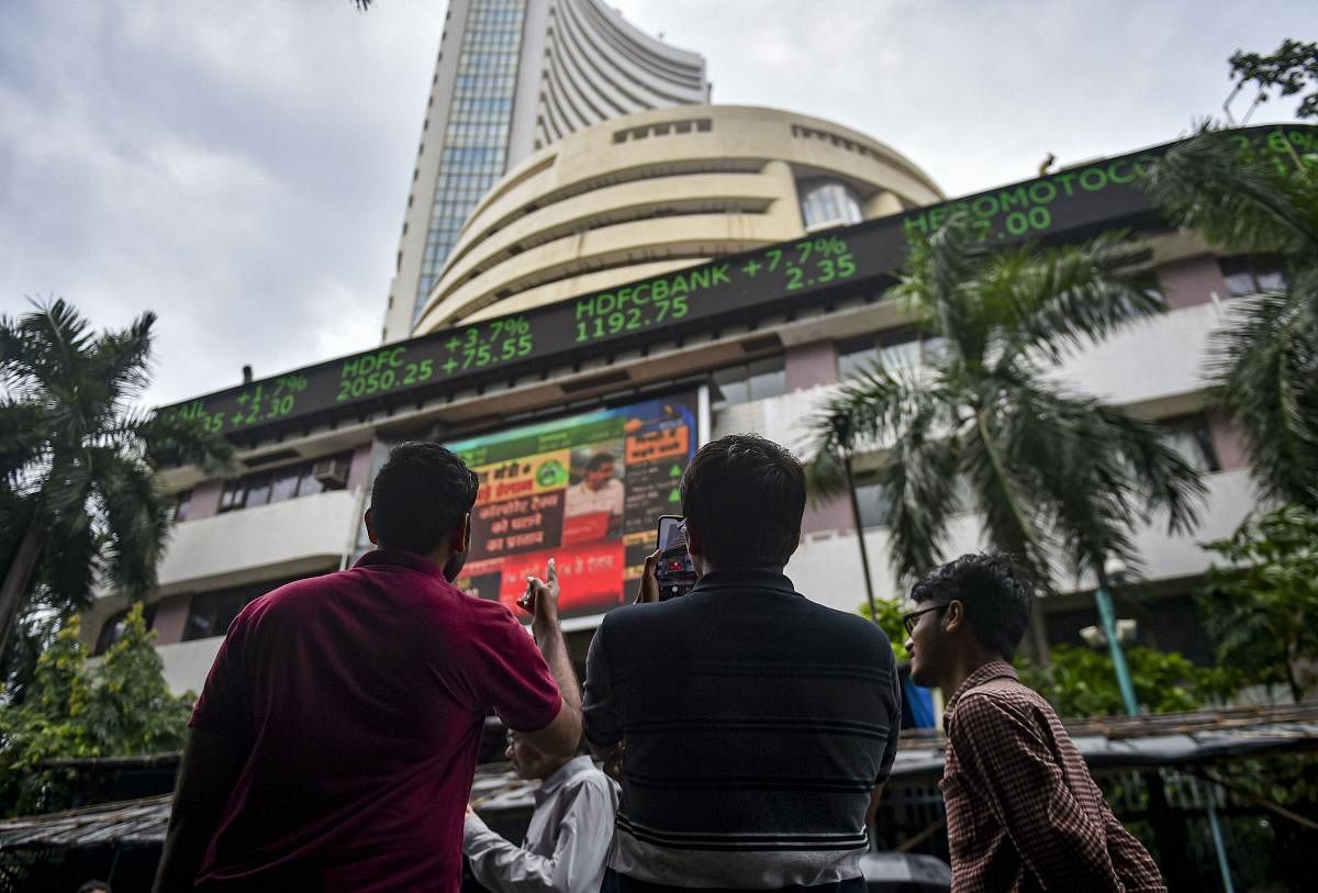 Bystanders react as they watch the stock prices displayed on a digital screen outside BSE building, in Mumbai. (PTI Photo)