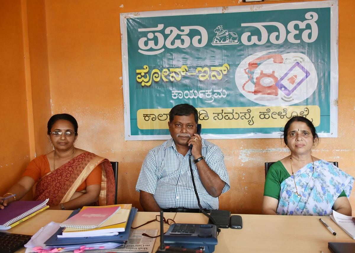 Deputy Director of Public Instruction Peregrine S Machado responds to the calls during Prajavani phone-in programme in Madikeri on Monday. Teachers Geetha Bhave and Rashmi George are seen. DH Photo