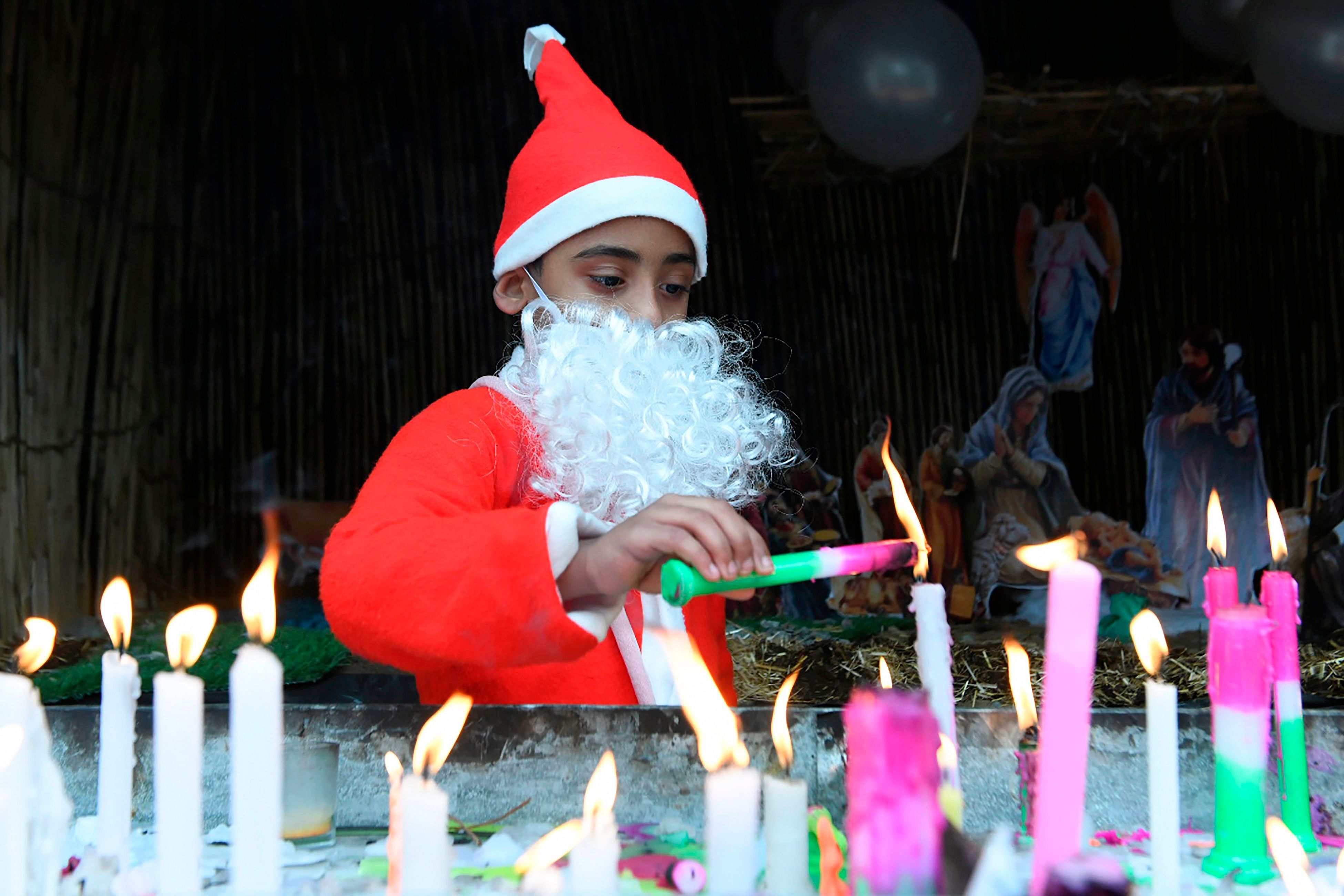 A child dressed as Santa Claus lights candles on Christmas Day. (AFP Photo)