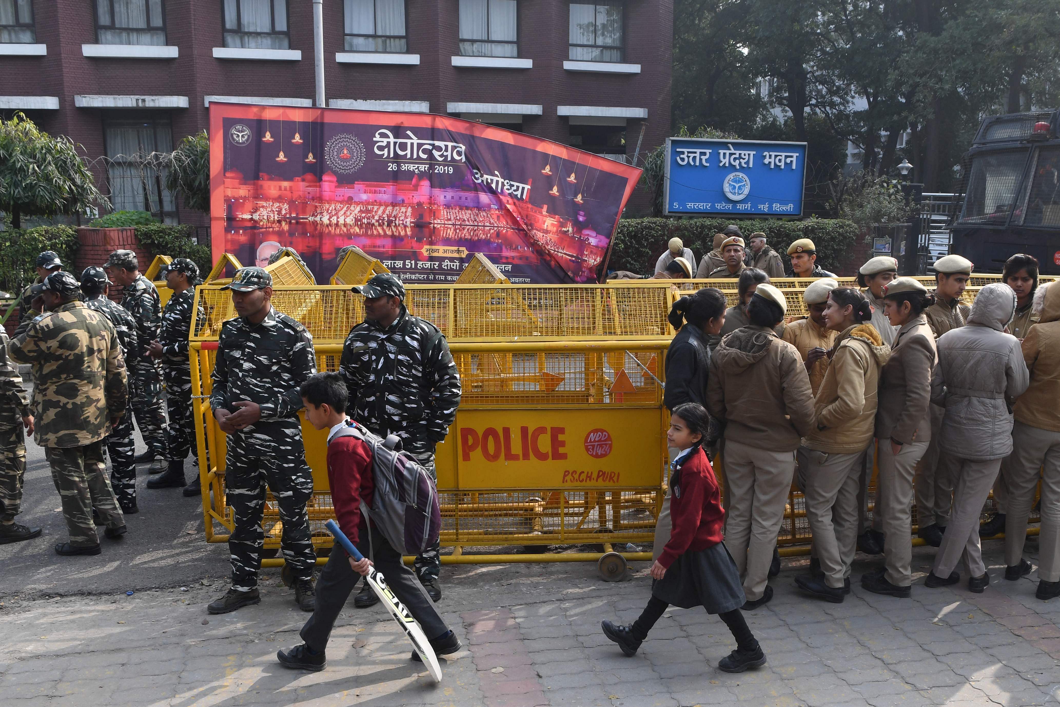 Schoolchildren walk past police outside the Uttar Pradesh Bhawan (state house) during a demonstration against the crackdown on protesters in Uttar Pradesh state. (AFP Photo)