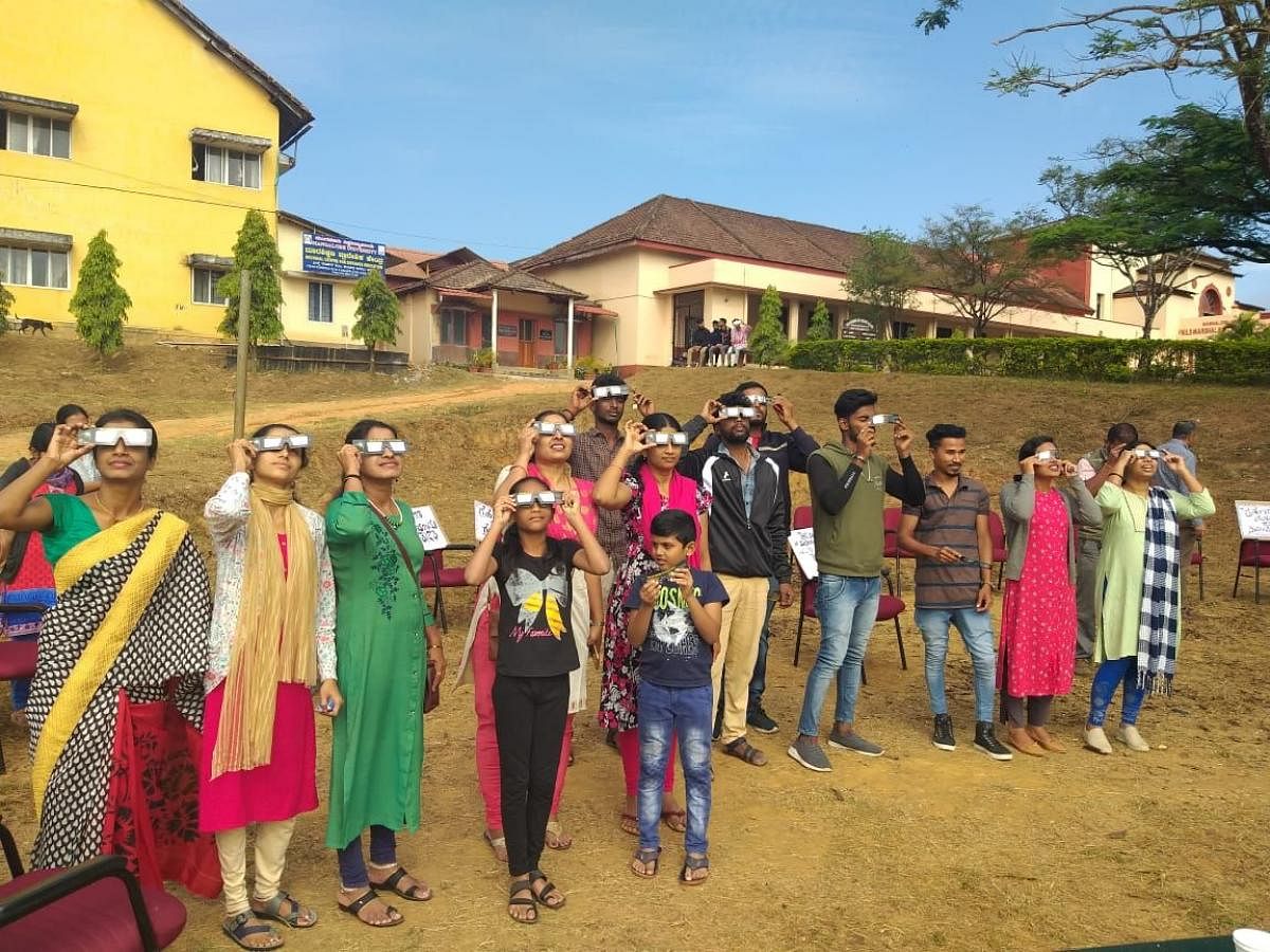 Students and alumni of Field Marshal K M Cariappa College, Madikeri, watch the solareclipse on Thursday.