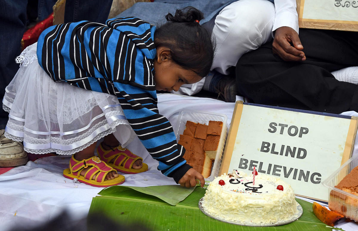 A young girl cuts a cake during an event organised to dispel myths about the eclipse on Thursday. DH photo/Pushkar V