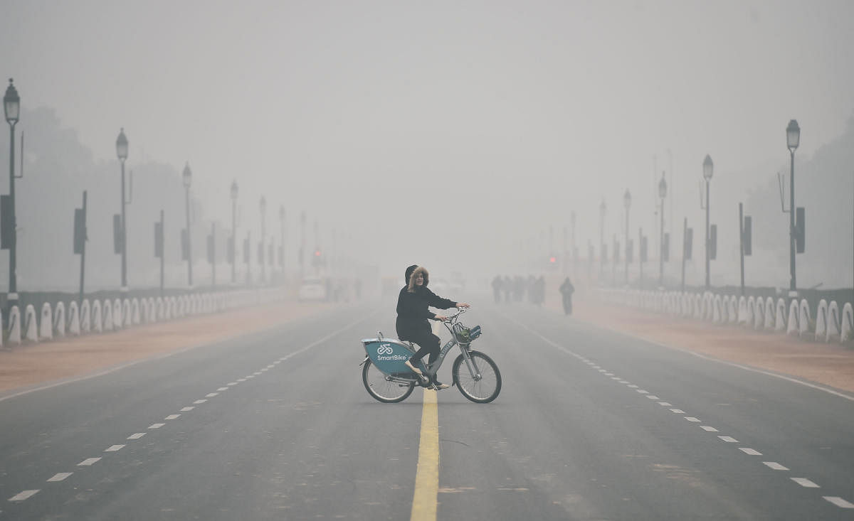A woman rides a bicycle on a cold and wintry morning at Rajpath in New Delhi. (PTI Photo)