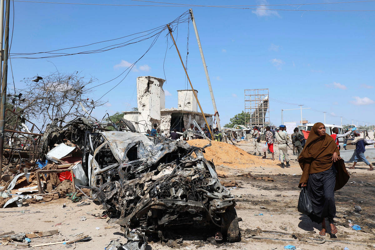 A Somali woman walks past a wreckage at the scene of a car bomb explosion at a checkpoint in Mogadishu. Photo/Reuters 
