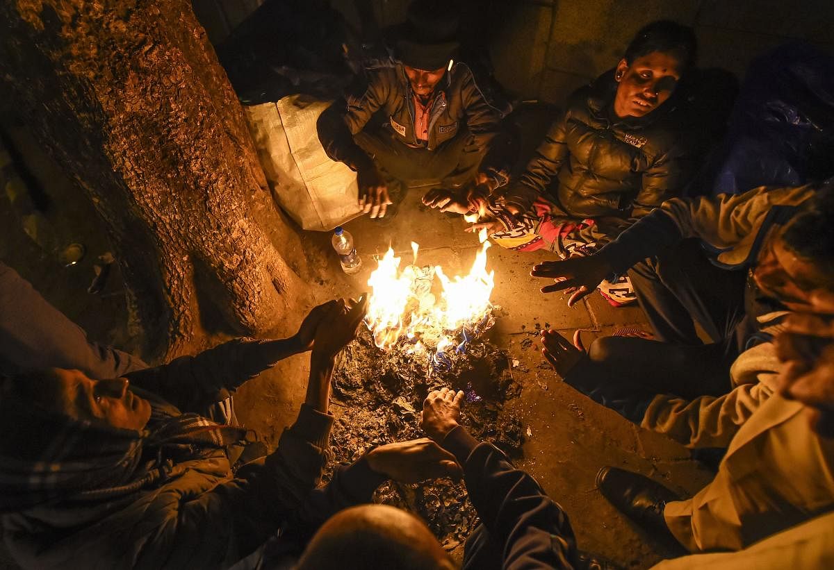 Workers warm themselves at a bonfire on a cold winter in in New Delhi. PTI