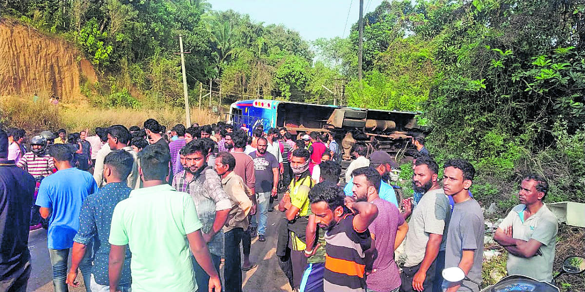 People gather around the private bus, which hit a car before falling into a roadside culvert, on the outskirts of Mangaluru on Saturday.