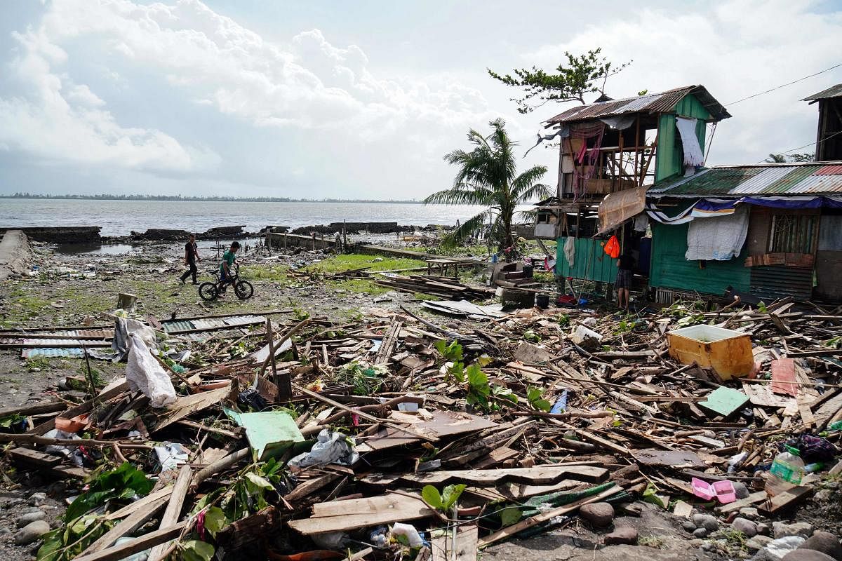 In this file photo taken on December 25, 2019, residents walk past a house damaged during Typhoon Phanfone in Tacloban, Leyte province in the central Philippines. (AFP Photo)