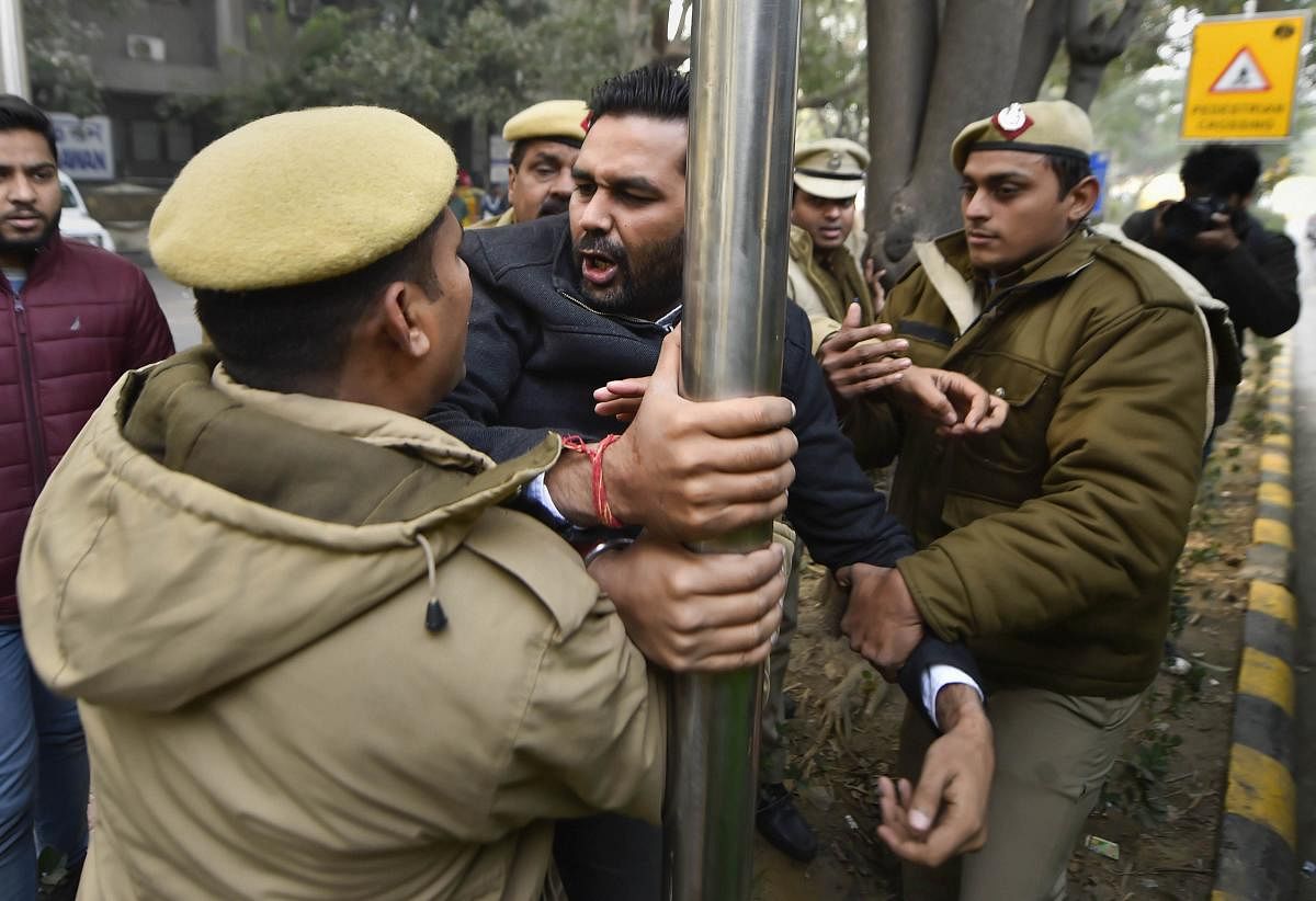 Police personnel attempt to detain a member of Indian Youth Congress during a protest against the alleged manhandling of Congress general secretary Priyanka Gandhi by Uttar Pradesh police, at UP Bhawan in Delhi, Sunday, Dec. 29, 2019. (PTI Photo)
