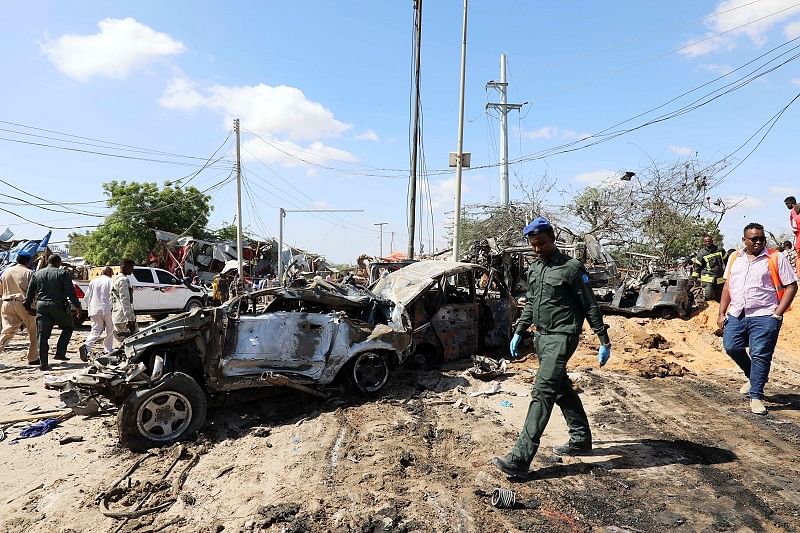 A Somali police officer walks past a wreckage at the scene of a car bomb explosion at a checkpoint in Mogadishu, Somalia. (Reuters Photo)