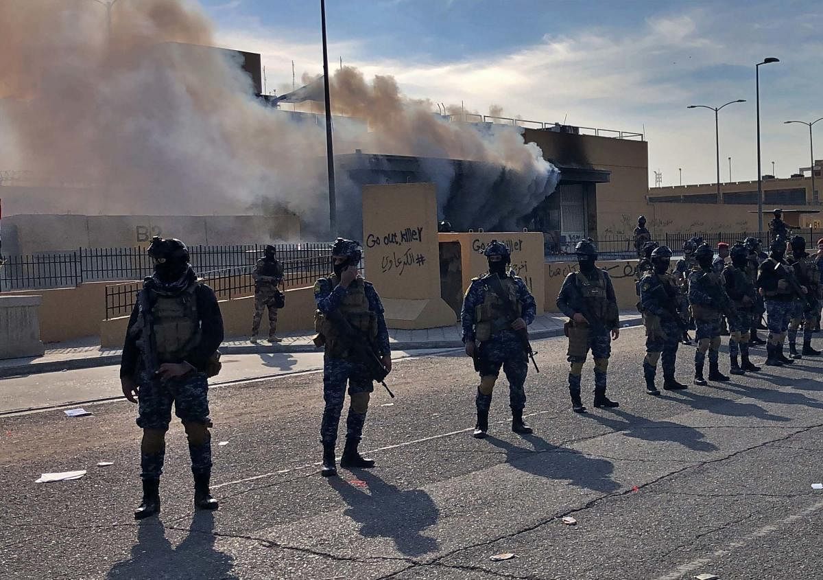  Iraqi security forces stand guard as smoke rises from the U.S. embassy compound in Baghdad, Iraq, Wednesday, Jan. 1, 2020. AP