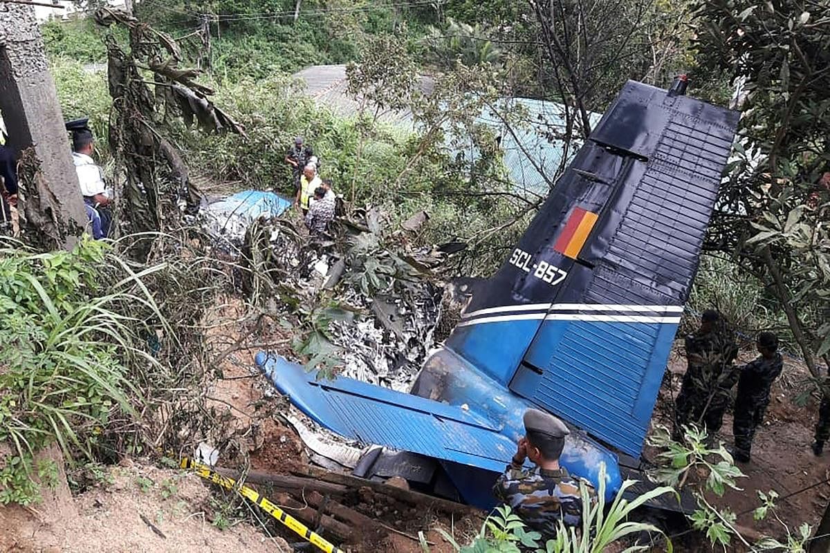 Rescue workers inspect the wreckage of a Sri Lankan air force plane that crashed in Haputale on January 3, 2020. - A Sri Lankan air force plane crashed in a tea-growing mountainous region on January 3, killing the four crew on board, a military official said. (Photo by STR / AFP)