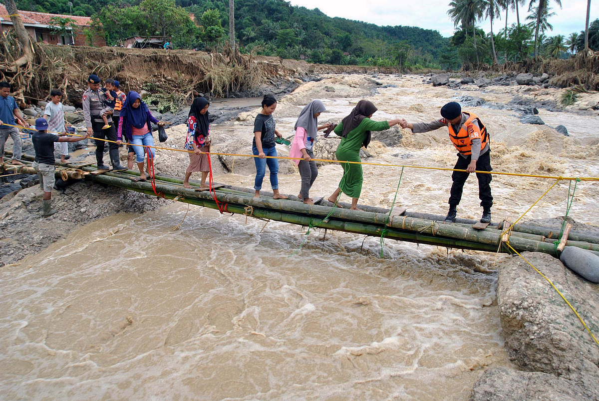Police officers help people to get through an emergency bridge over the Cidurian river in Bogor, Indonesia, January 3, 2020. (Reuters Photo)