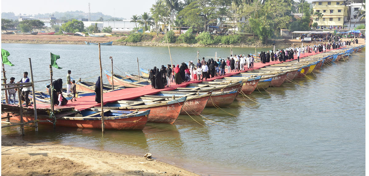 People cross the temporary bridge made of boats to reach Rahmania Dargah Masjid Shariff at Adyar-Kannur on Sunday. DH PHOTO