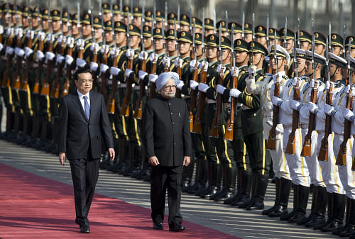 Prime Minister Manmohan Singh, right, is accompanied by Chinese Premier Li Keqiang, left, as they inspect an honor guard during a welcome ceremony outside the Great Hall of the People in Beijing, China Wednesday, Oct. 23, 2013. AP photo