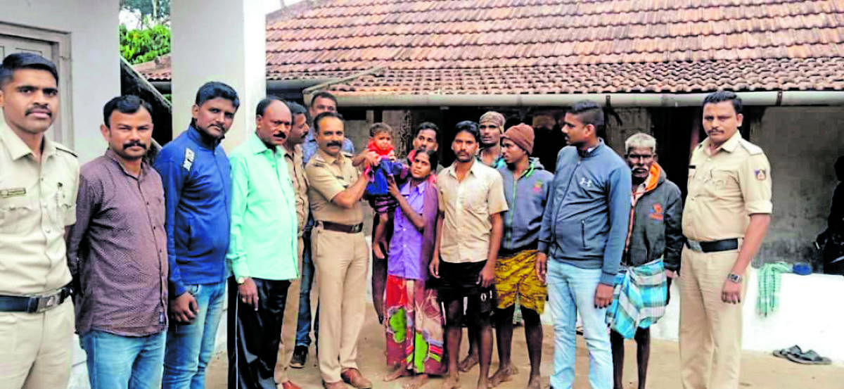Police and forest department officials hand over Nityashree, the lost child, to her parents. DH Photo