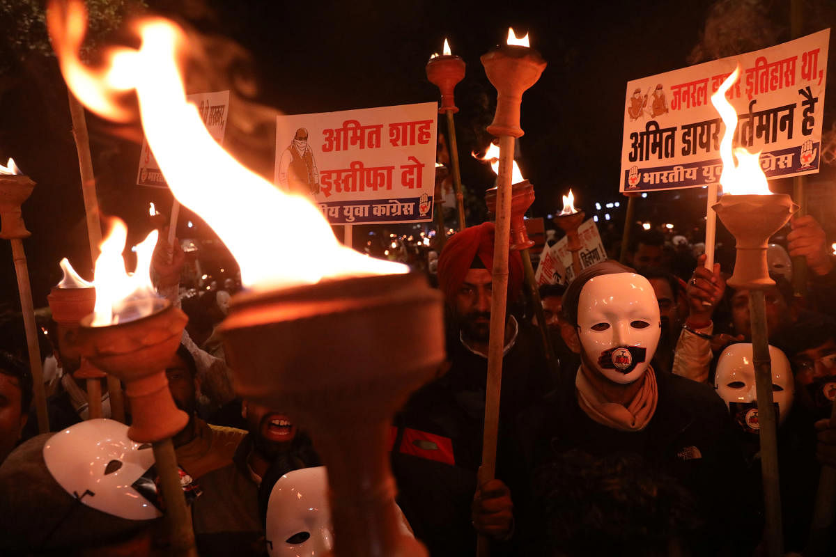 Supporters of the youth wing of India's main opposition Congress party wearing masks carry torches during a protest against the attacks on the students of Jawaharlal Nehru University (JNU). (Reuters Photo)