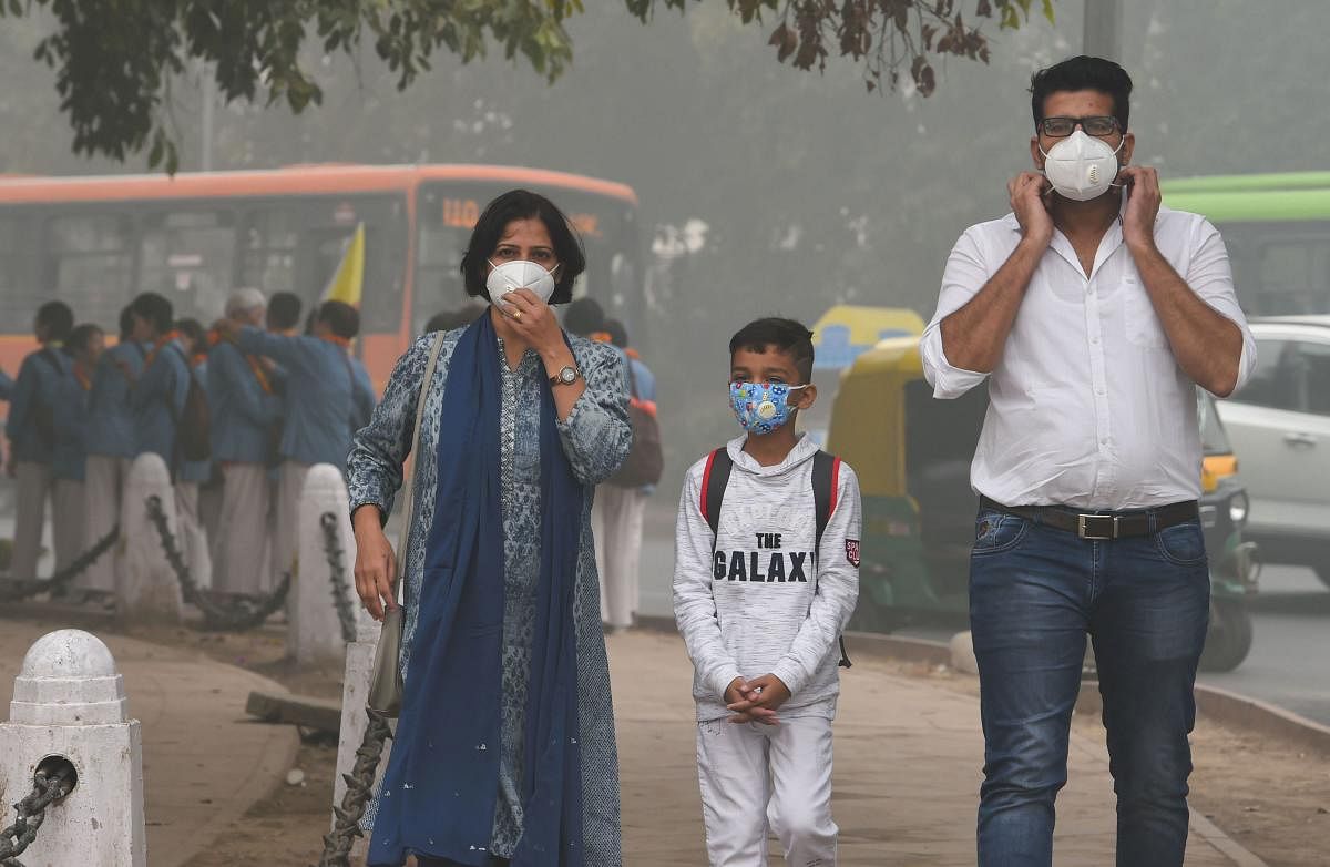 People wear masks amid heavy smog as the air quality further dipped in New Delhi on Sunday. PTI