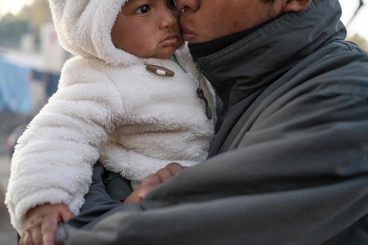 An unidentified man from Guerrero State, who is fleeing cartel violence, kisses his daughter as they prepare for another cold night in the camp in Ciudad Juarez, Mexico. (Photo by AFP)