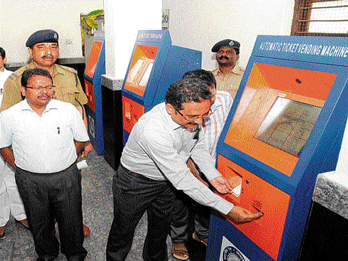 Divisional Railway Manager Rajkumar Lal operates the newly-installed automatic ticket vending machine at the main railway station in Mysuru on Tuesday. Senior Divisional Commercial&#8200;Manager&#8200;K&#8200;Anil Kumar looks on. DH photo