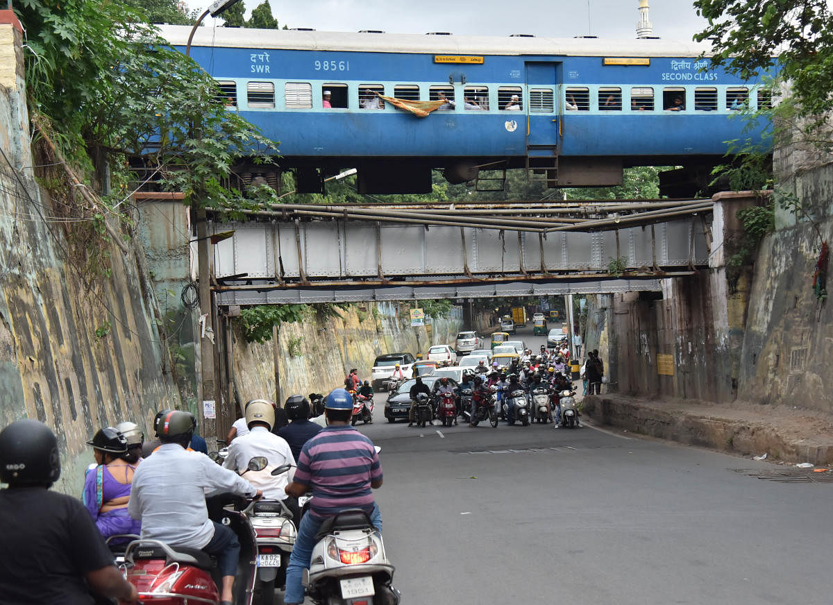 Two-wheelers wait patiently under the railway overbridge for the train to pass at Seshadripuram. DH Photo/Janardhan B K
