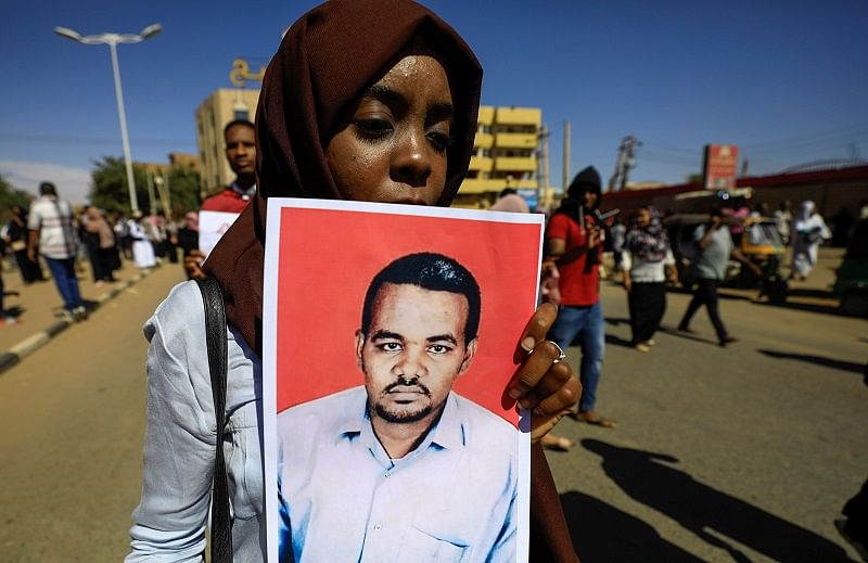 A Sudanese woman carries a portrait of the teacher Ahmed al-Khair as she celebrates after the sentencing of 27 members of the national intelligence service to death by hanging over the killing of a teacher in detention in February during protests that led to the overthrow of former president Omar al-Bashir. (Reuters Photo)
