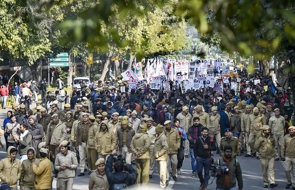 Police personnel walk in front of JNU students' protest march from Mandi House to HRD Ministry, demanding removal of the university vice-chancellor, at Ferozeshah Road in New Delhi, Thursday, Jan. 9, 2020. (PTI Photo/Ravi Choudhary)
