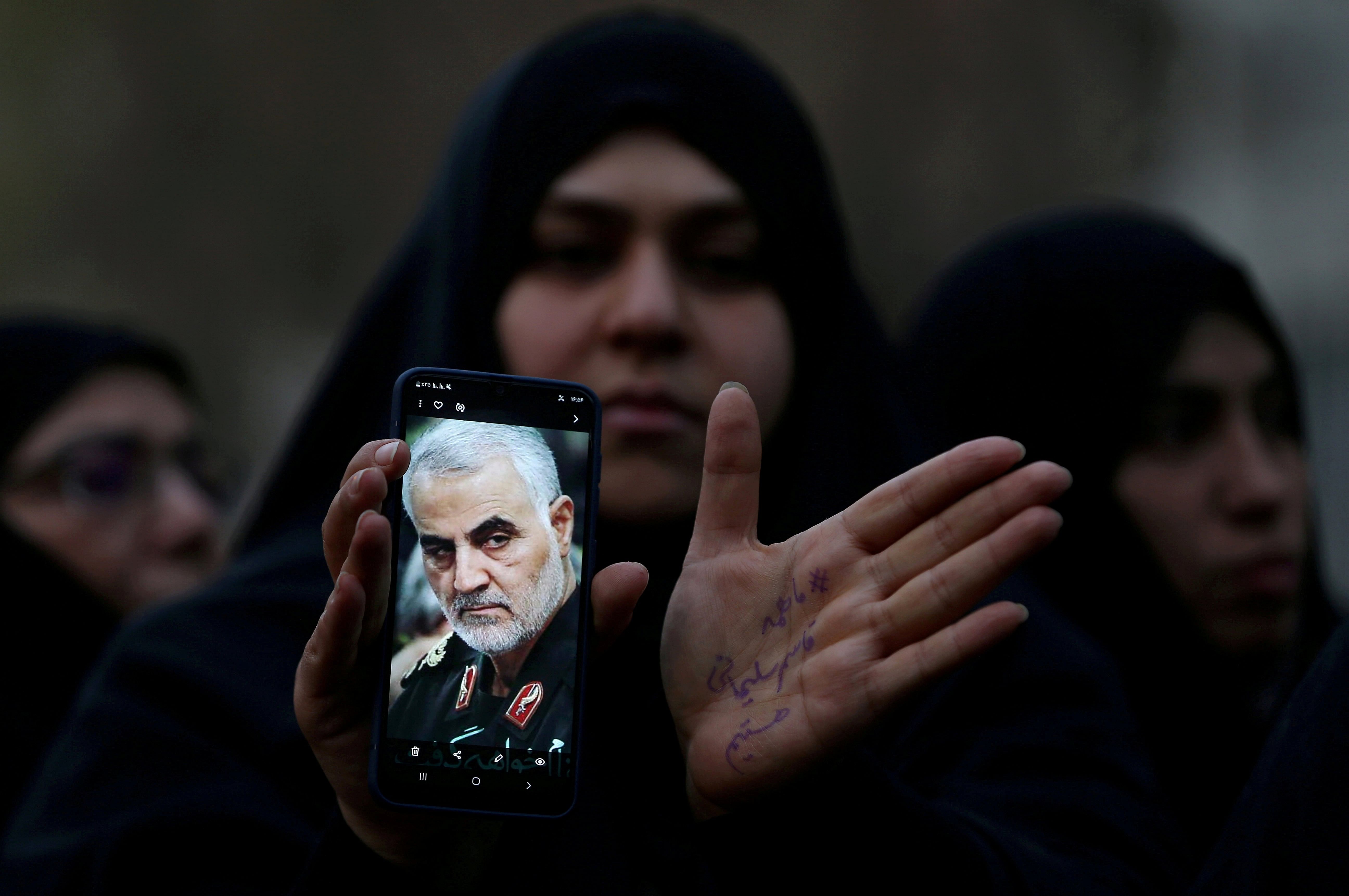 An Iranian woman shows a photo of the late Iranian Major-General Qasem Soleimani, during a protest against the killing of Soleimani, head of the elite Quds Force, and Iraqi militia commander Abu Mahdi al-Muhandis. (Reuters Photo)