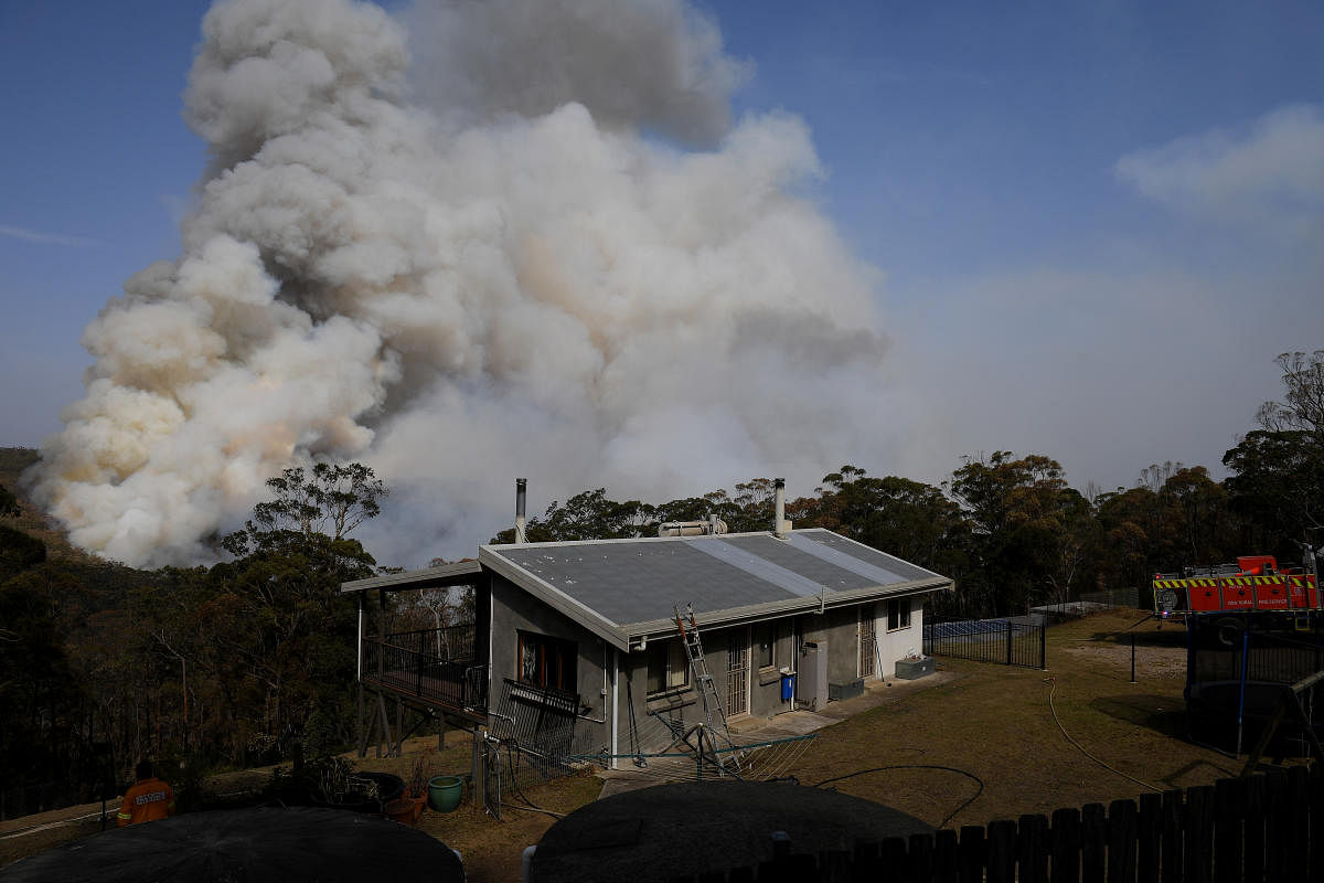 NSW Rural Fire Service crews watch on as a fire burns in bushland close to homes at Penrose in the NSW Southern Highlands, south of Sydney. Reuters