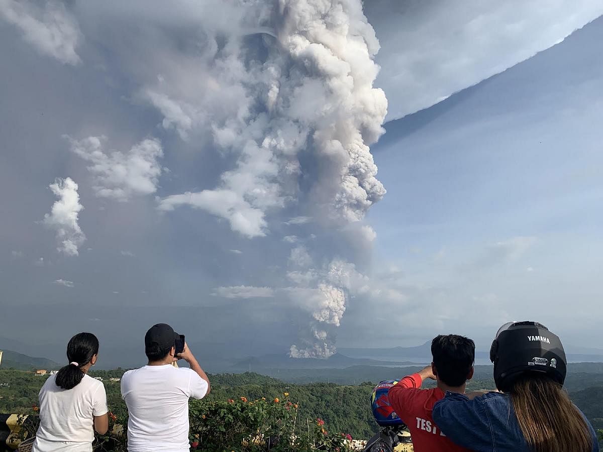  People take photos of a phreatic explosion from the Taal volcano as seen from the town of Tagaytay in Cavite province, southwest of Manila. AFP