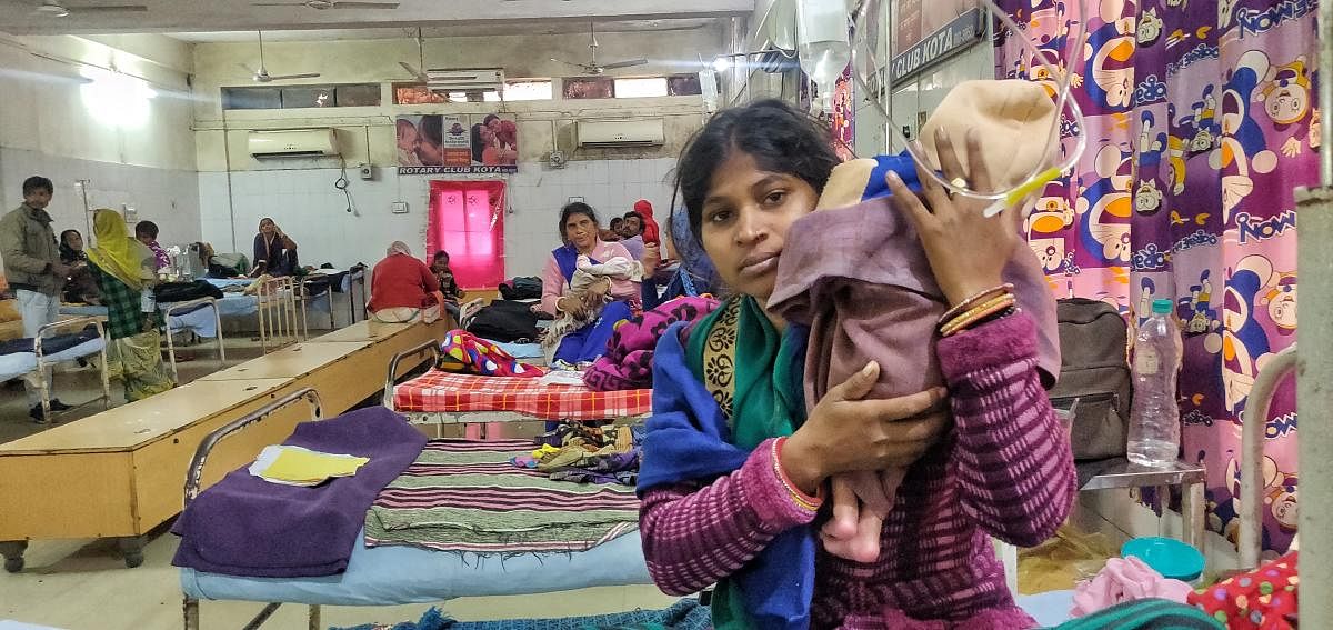 A mother holding her baby inside the general ward of the paediatrics department at the J K Lon Hospital in Kota, Rajasthan. The kin of patients wait outside the hospital, which is being renovated. (Credit: DH Photo)