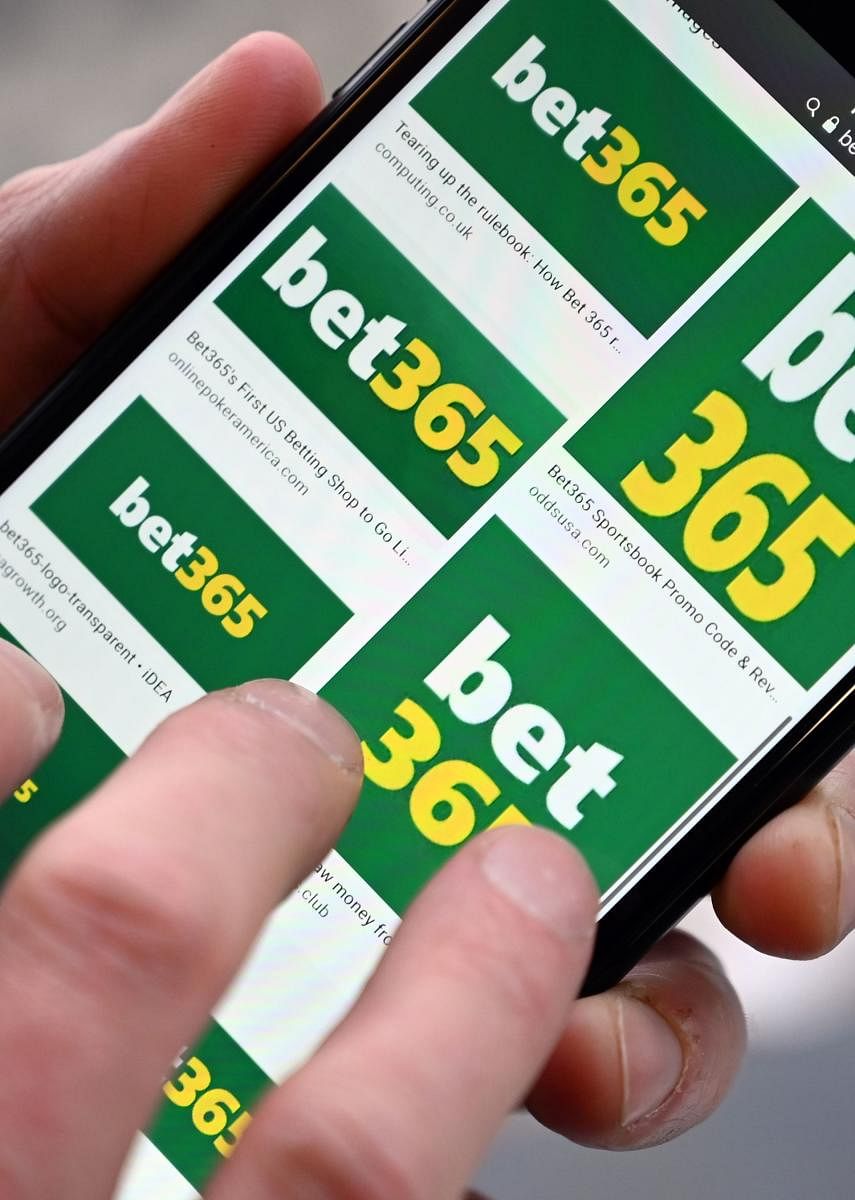 A man poses for a photograph with the online gambling website Bet365 displayed on a smartphone. (AFP PHOTO)