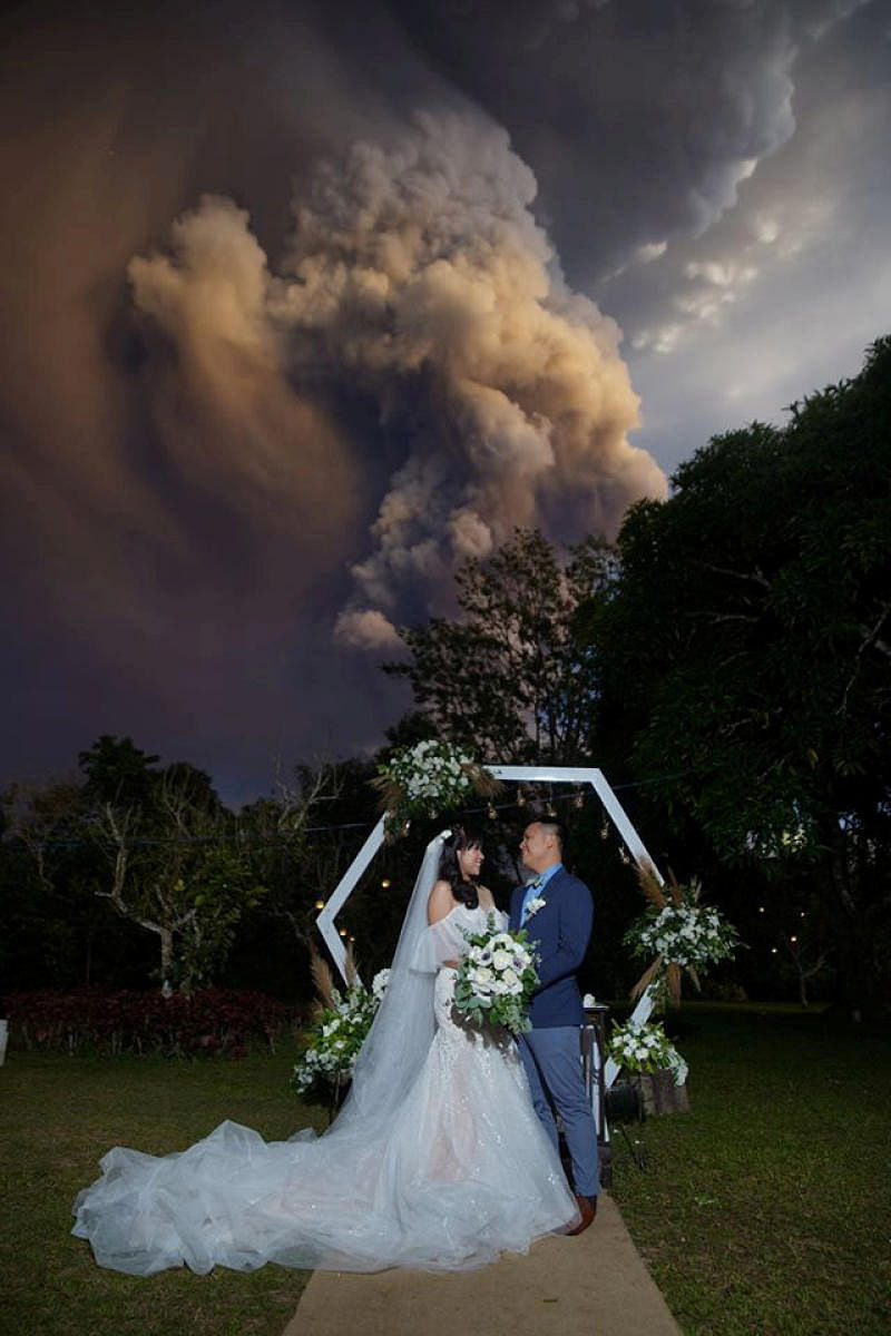 A couple attends their wedding ceremony as Taal Volcano sends out a column of ash in the background in Alfonso, Cavite, Philippines, January 12, 2020.