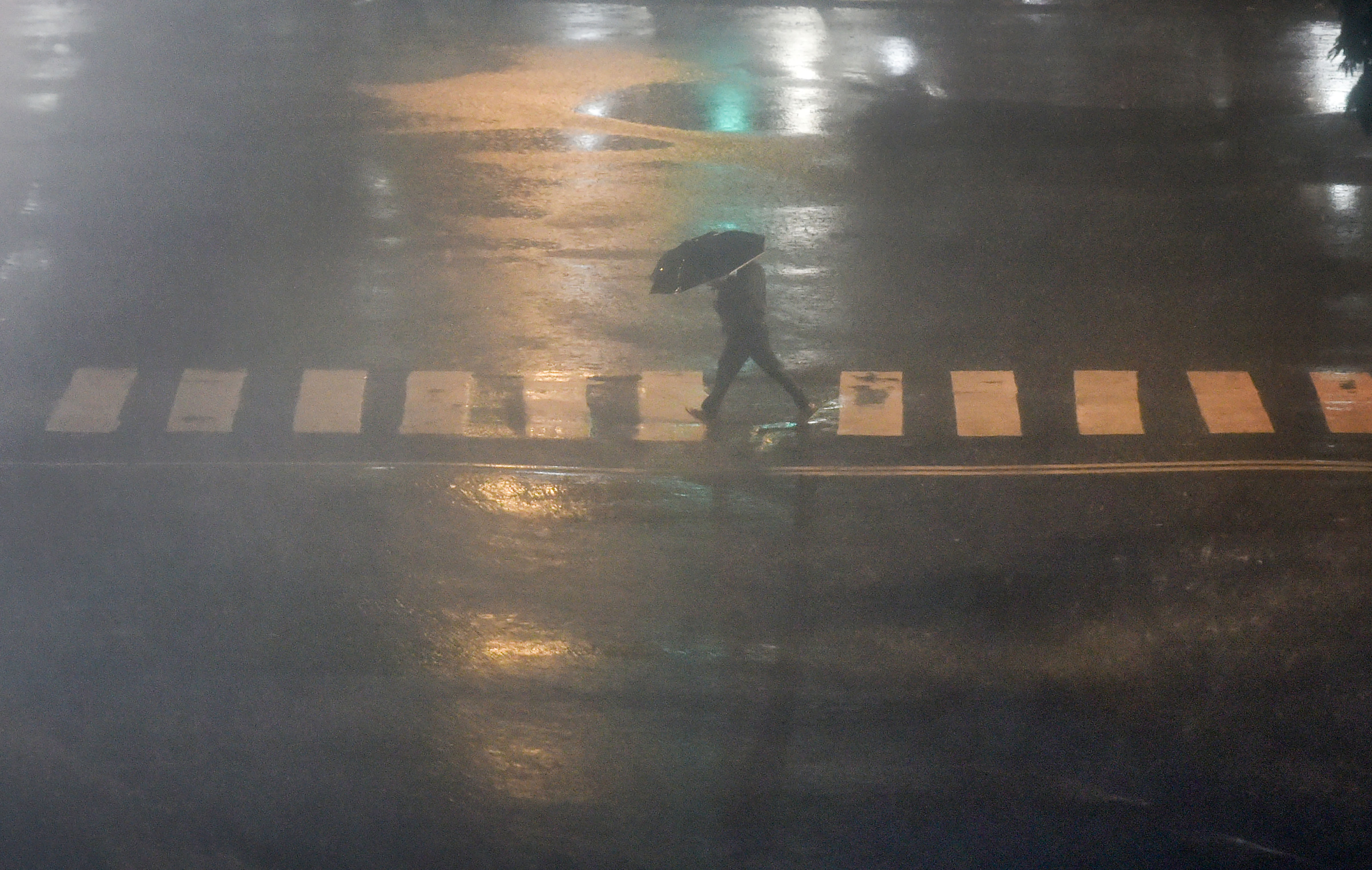 A pedestrians takes cover under an umbrella during heavy monsoon rain in Mumbai. (PTI Photo)