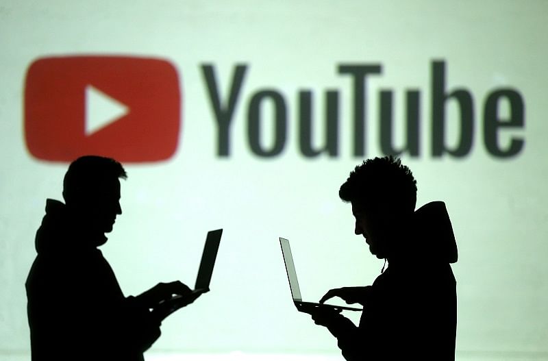 Silhouettes of mobile device users are seen next to a screen projection of Youtube logo in this picture illustration taken. (Reuters Photo)