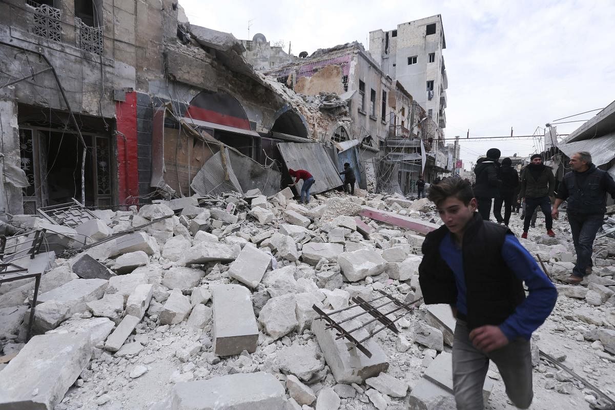 People walk past destruction by the government airstrikes in the town of Ariha. (AP Photo)