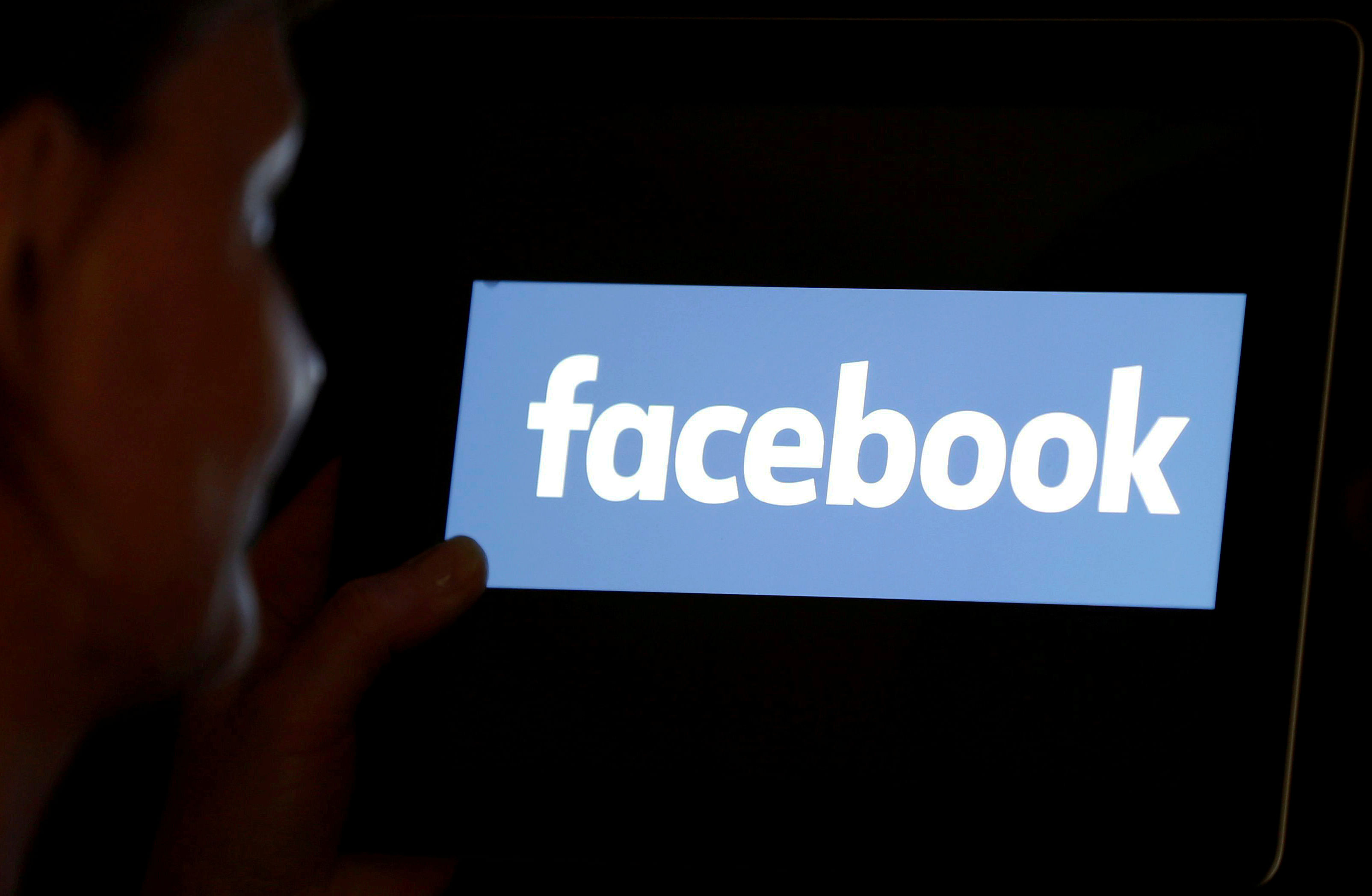 A woman looks at the Facebook logo. (Reuters Photo)